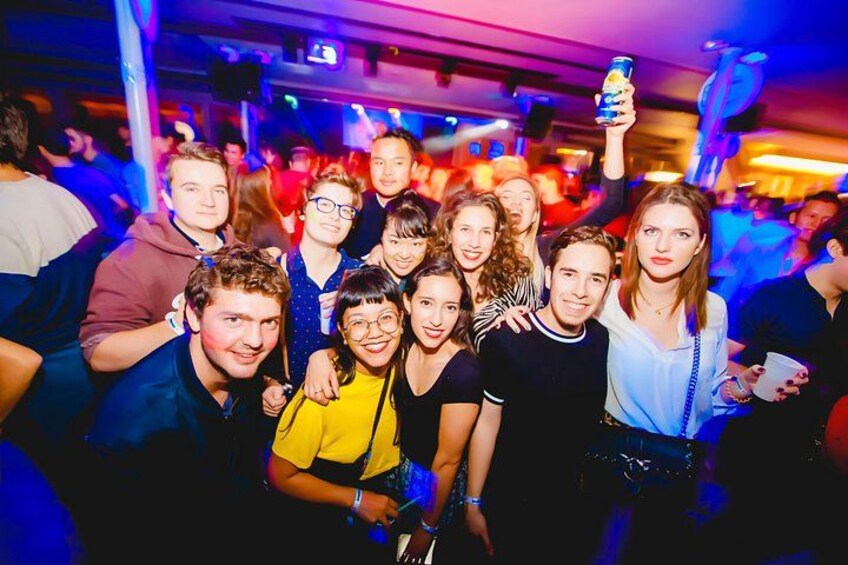 A group of people at a social event, possibly a party or club, with a person holding a can. 1