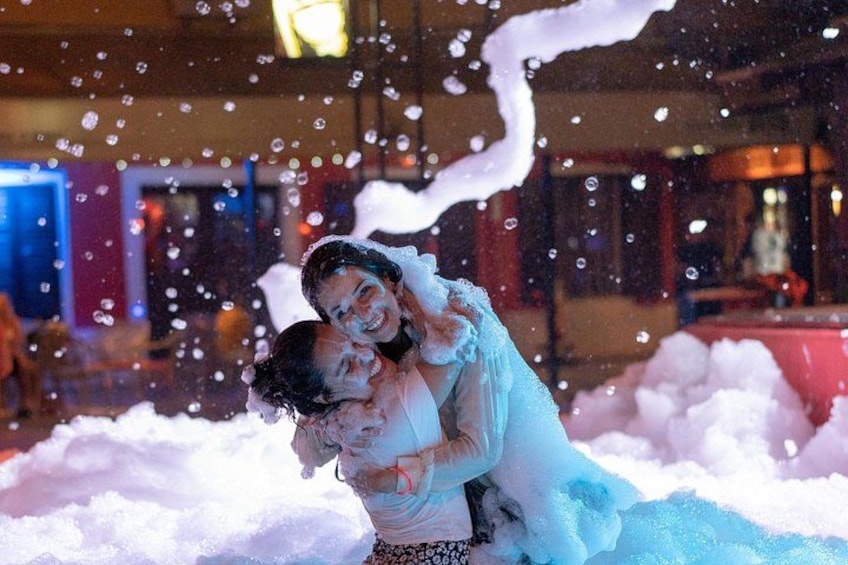 A person carrying another person in a snowy environment with bubbles floating around. 4