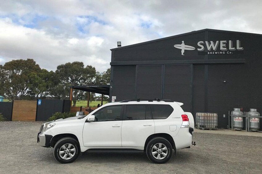 A white SUV parked in front of a building with the sign 'SWELL BREWING CO.' 4