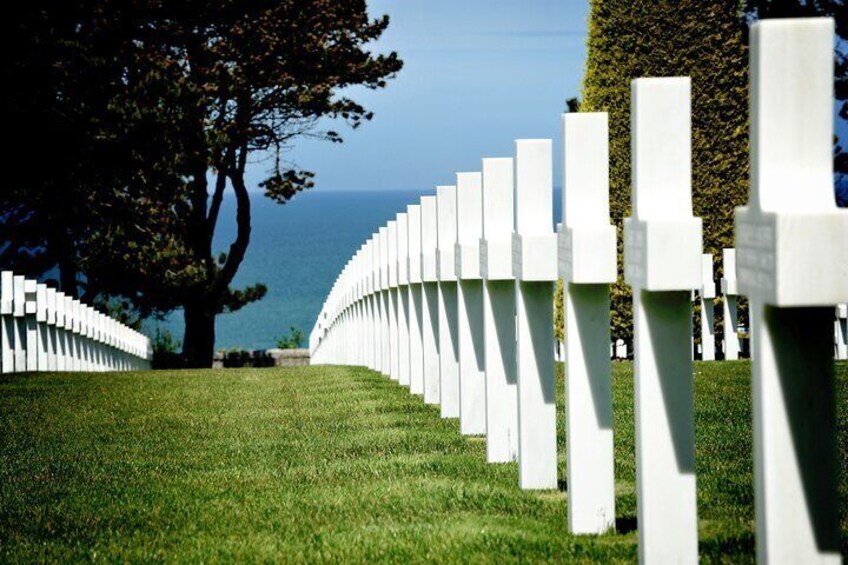 A cemetery with white crosses arranged in rows. 5