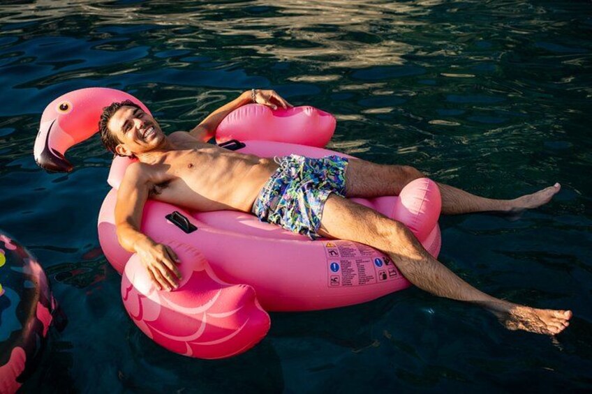 Una persona flota sobre un flamenco inflable rosa en el agua. 2