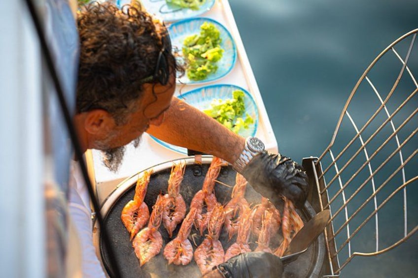 En person som grillar räkor på en grill. 1