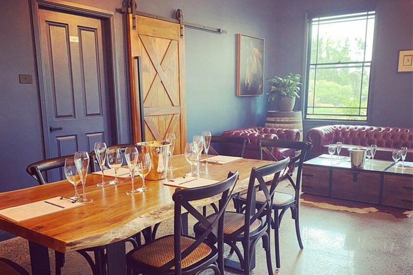 A dining area with a wooden table set for a meal, a red leather couch, and a large window with a view of greenery. 2