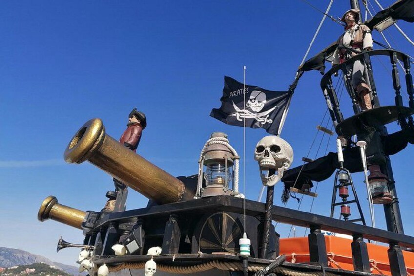 Un navire pirate arborant un pavillon orné d’un crâne et de deux os croisés, muni d’un grand canon, et sur lequel se trouve une personne déguisée en pirate. 2
