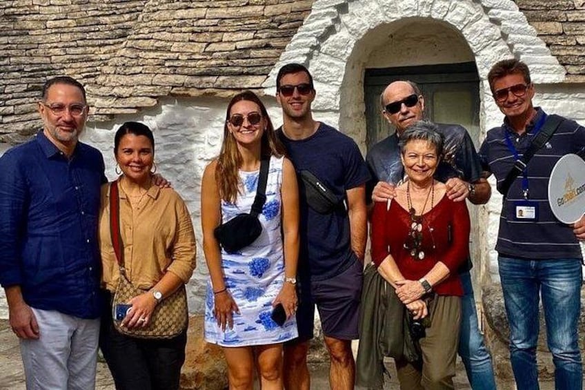 A group of people standing in front of a stone building with an arched doorway. 2