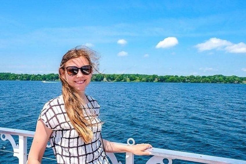 Iemand staat op een boot, met een wateroppervlak en een groene oever in de verte. 4