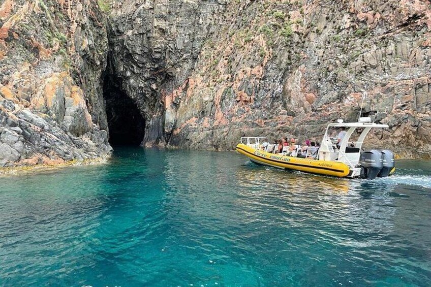 Un bote amarillo navegando por una vía fluvial rocosa con la entrada de una cueva. 3