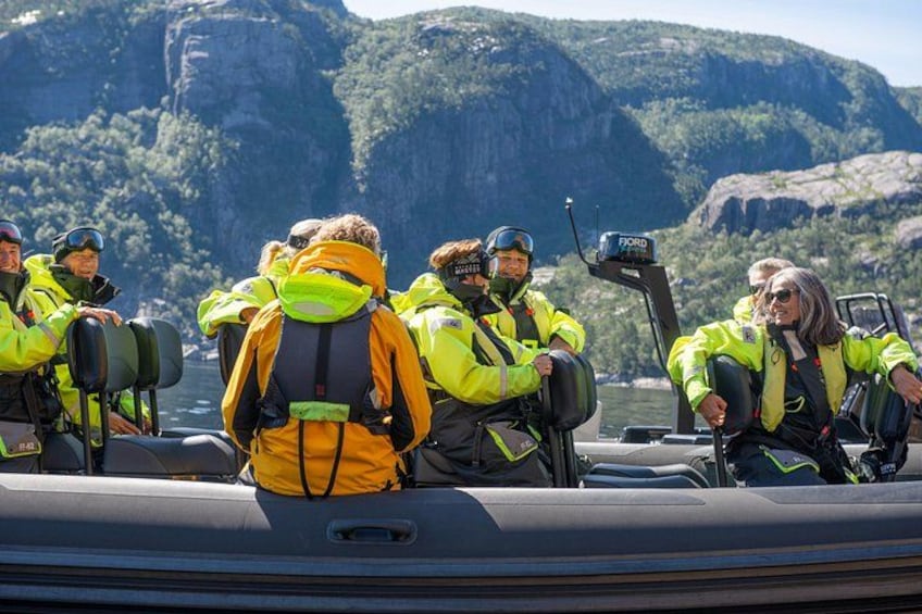 Eine Gruppe von Personen in gelben Westen auf einem Boot vor einer felsigen Landschaft. 3
