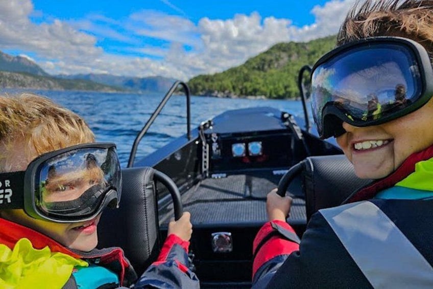 Zwei Personen in einem Boot mit einem See und Hügeln im Hintergrund. 5