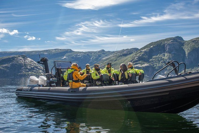 Eine Gruppe von Menschen auf einem Boot vor einer bergigen Landschaft. 1