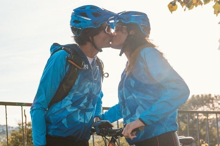 Dos personas con ropa y cascos de ciclismo, de pie junto a una bicicleta. 3