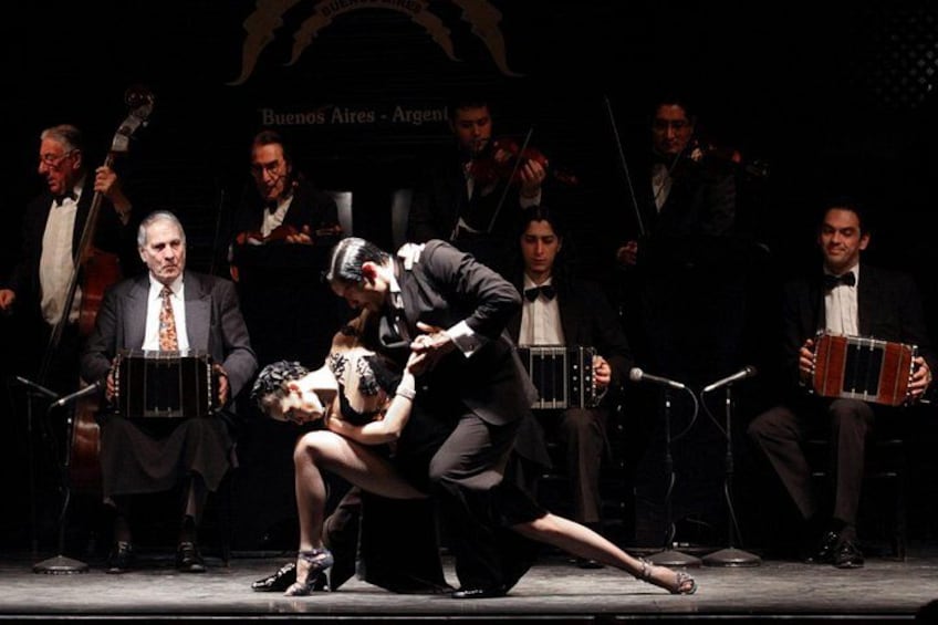 A group of musicians performing on stage with a woman kneeling in the center. 5
