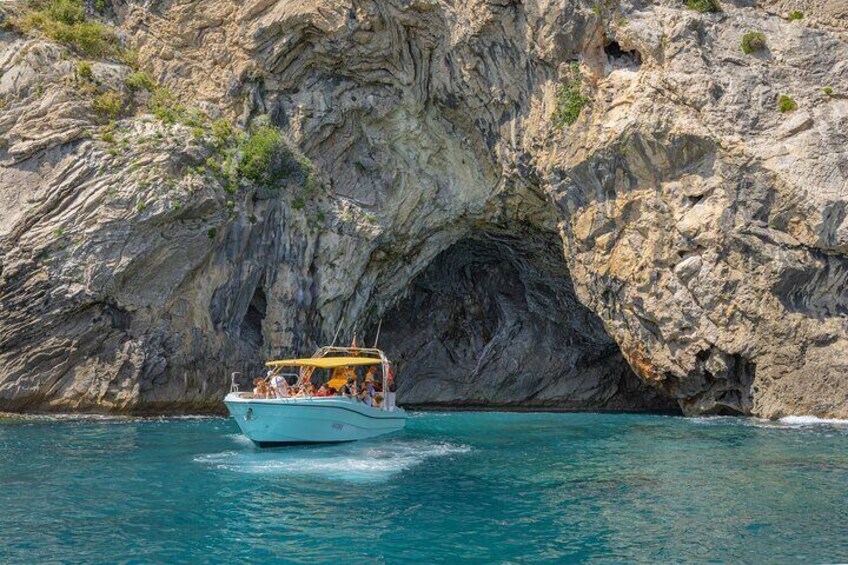 A boat with passengers navigating through a narrow waterway between rocky cliffs. 5