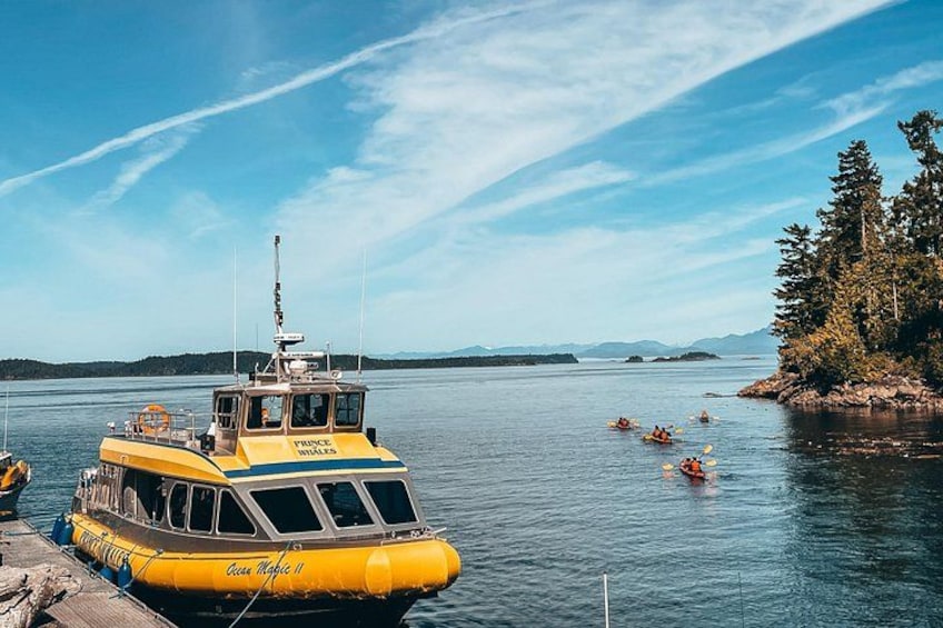 Un bateau jaune, baptisé « Coco Mahie II », était amarré à un quai, et des personnes pratiquaient le kayak dans l’eau. 2