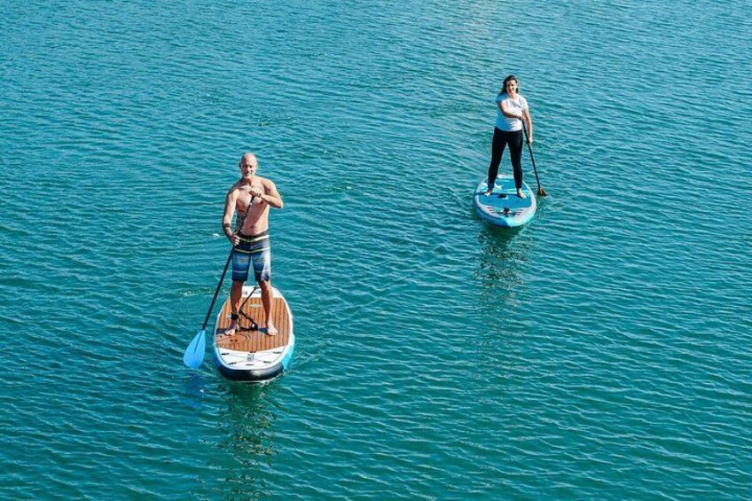 Due persone che fanno paddleboard su acque calme. 1