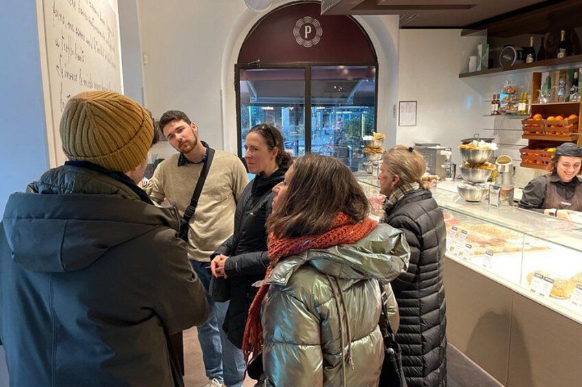 Eine Gruppe von Personen in einem Café mit einer Theke, auf der Speisen präsentiert werden. 2