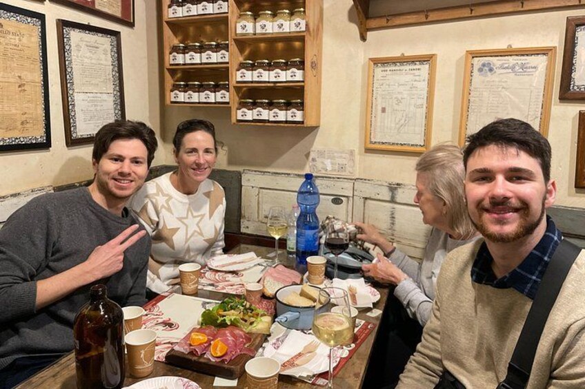 Eine Gruppe von Personen speist in einem Restaurant mit einem Holztisch, verschiedenen Speisen und einer blauen Wasserflasche. 5