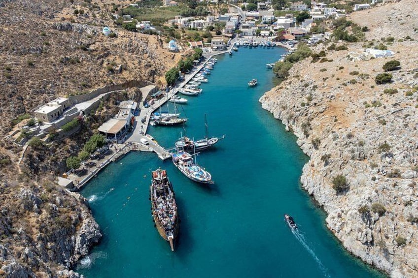 Un pueblo costero con un puerto deportivo, barcos y terreno rocoso. 3
