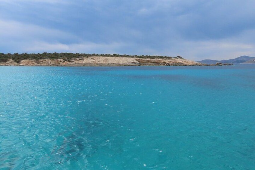 A turquoise sea with a sandy beach and distant mountains. 2
