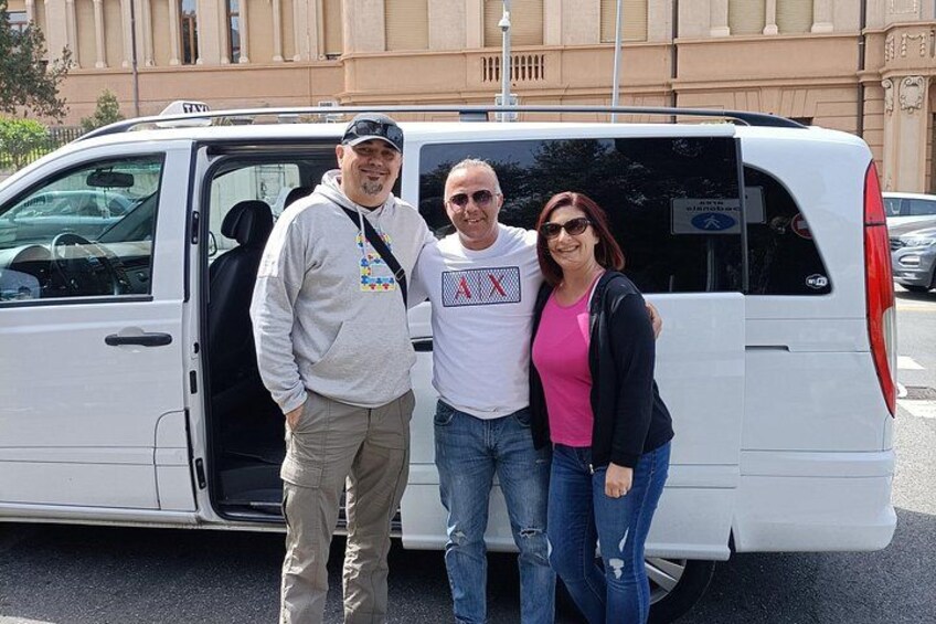 Tres personas de pie frente a una camioneta blanca con la puerta abierta. 2