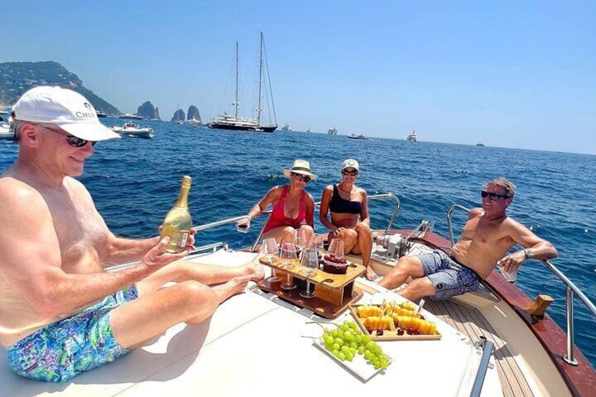 A group of people on a boat with a table set for a meal, surrounded by water and boats in the distance. 1