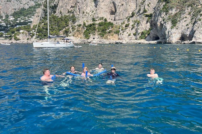 People floating on water with a sailboat in the background. 5