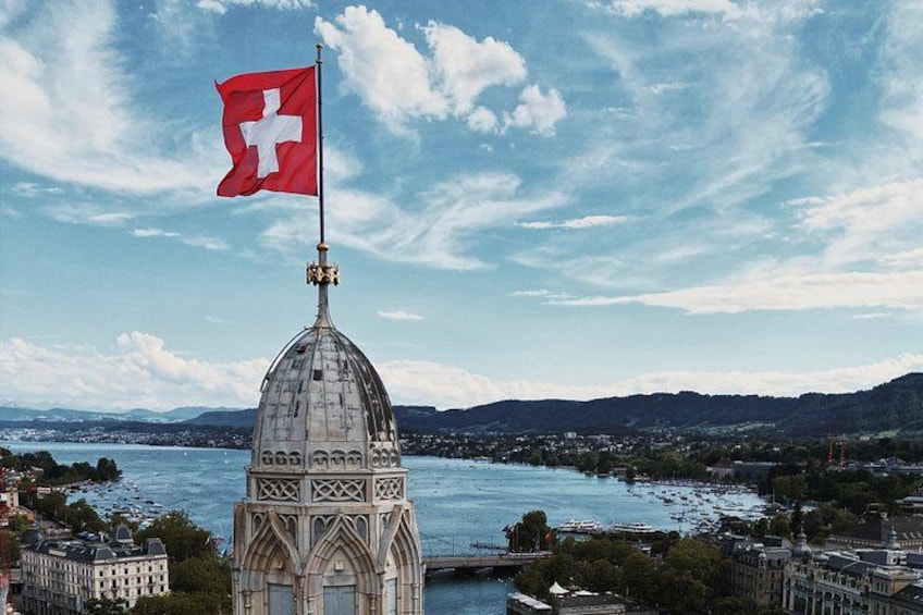 Ein Kuppelgebäude mit Schweizer Flagge, einem Fluss und einer Berglandschaft im Hintergrund. 2