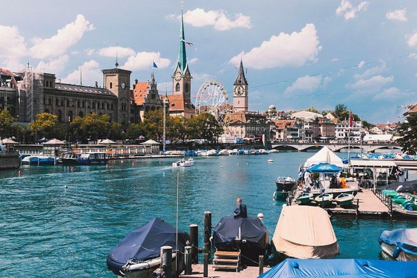Ein Hafen mit Booten, einem Riesenrad und historischen Gebäuden. 3