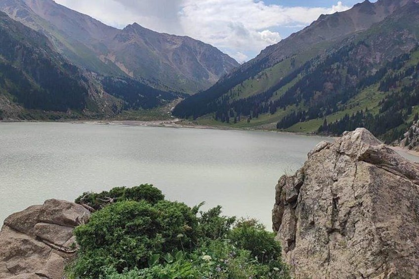 A mountain lake surrounded by rocky terrain and dense greenery. 2