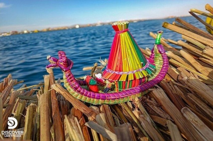 Een kleurrijke boot van riet met een kegelvormige constructie bovenop, drijvend op het water. 5