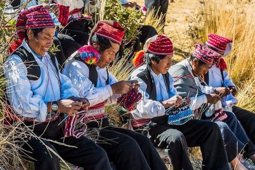 People wearing traditional attire, sitting outdoors, engaged in a craft activity. 1
