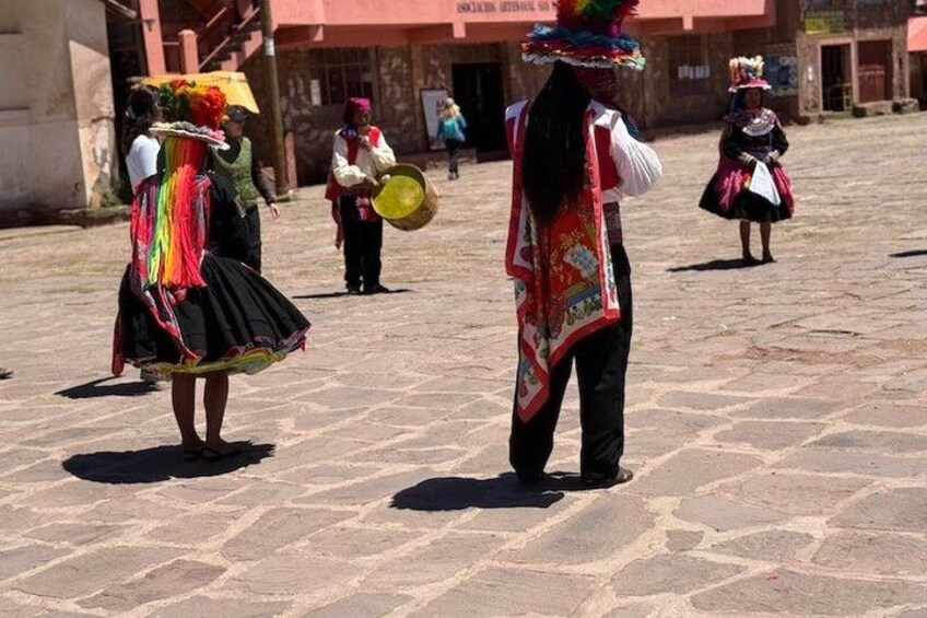 A street with people in traditional attire, a building with a sign, and a paved ground. 2