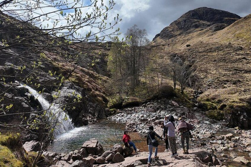 A waterfall, rocky terrain, and hikers in a mountainous area. 1