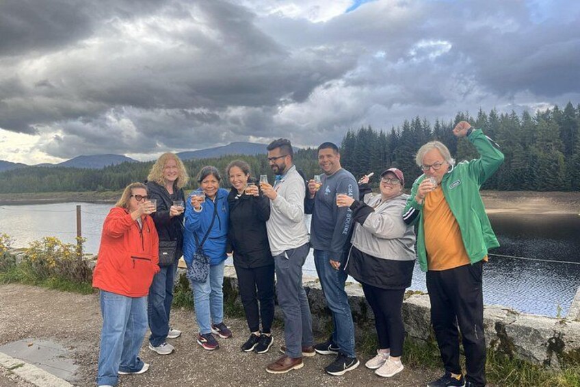 A group of people standing by a lake with mountains in the background. 4
