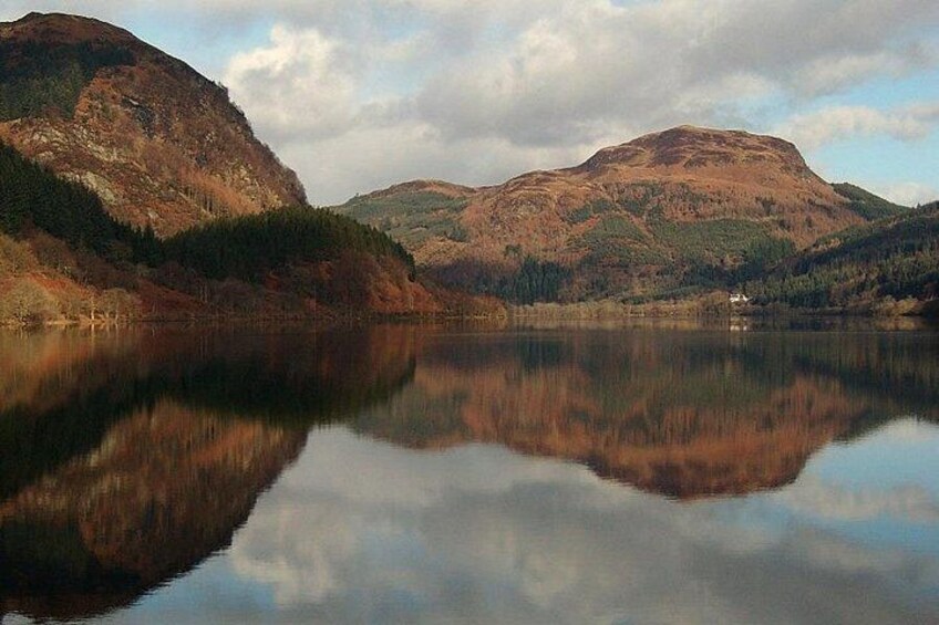 Un lago tranquilo con reflejos de montañas, rodeado de colinas boscosas. 3