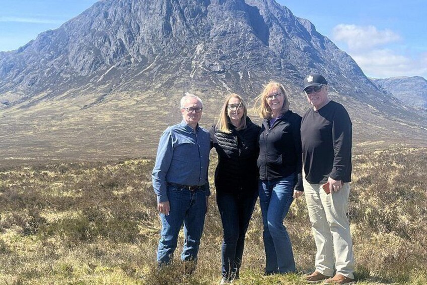 A group of people standing in a grassy field with a mountain in the background. 4