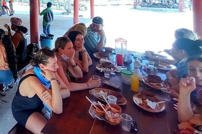 Un groupe de personnes est assis autour d’une table, devant de la nourriture et des boissons. 5