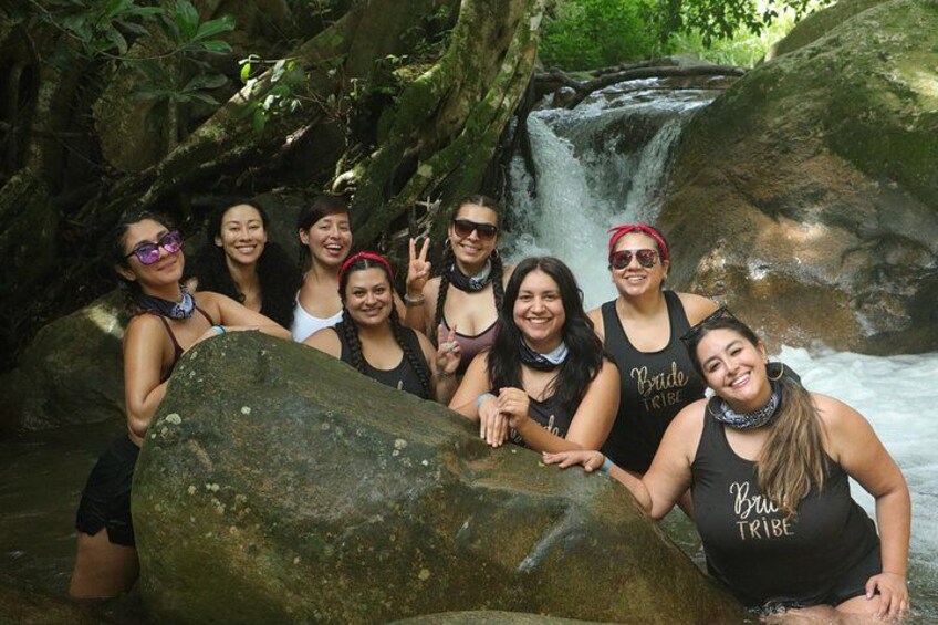 Un groupe de personnes posant devant une cascade, avec une végétation luxuriante en arrière-plan. 2