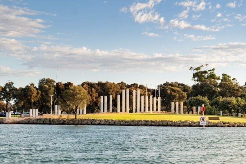 A waterfront with a row of white columns, a grassy area, and trees in the background. 4