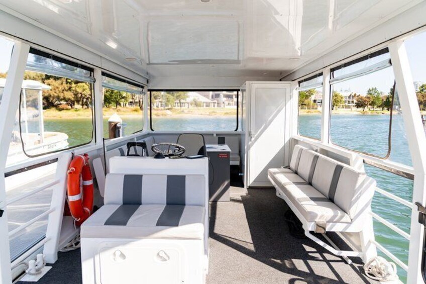 A boat interior with a white and gray striped sofa, a steering wheel, and a lifebuoy. 5
