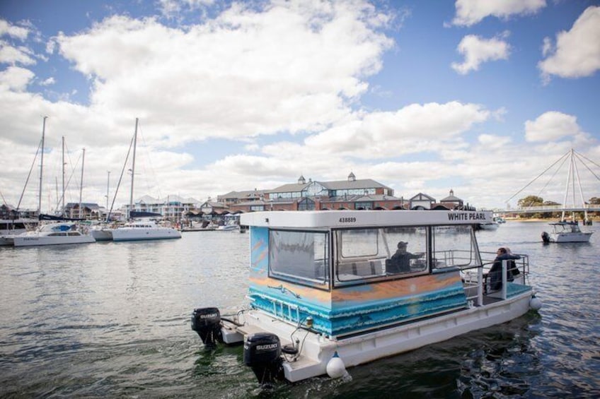 A boat named 'WHITE PEARL' docked at a marina with sailboats in the background and a bridge in the distance. 3