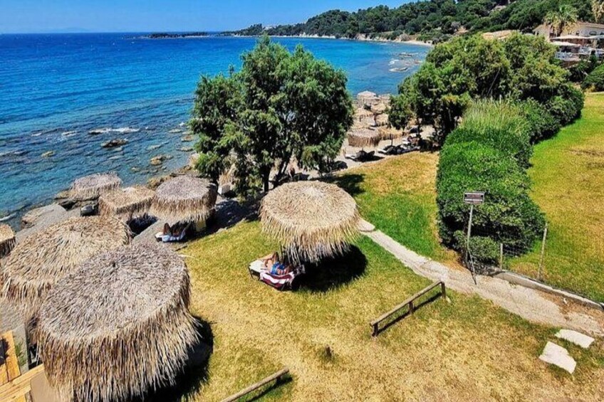 A coastal area with thatched-roof structures, a pathway, and a view of the sea. 2
