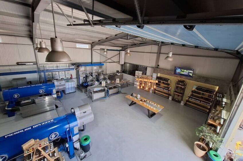 A spacious industrial kitchen with large blue machinery, a display counter, and shelves stocked with bottles. 2