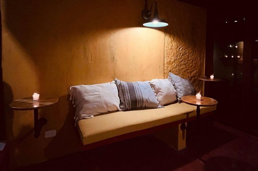 Un rincón acogedor con un sofá, dos mesitas redondas y lámparas de pared. 2
