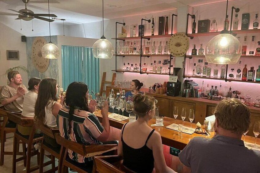 Un groupe de personnes est assis au bar, devant des bouteilles et des verres. 4