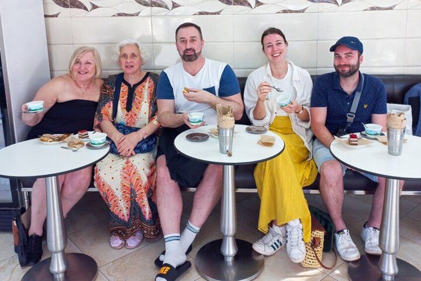 Un grupo de cinco personas sentadas en mesas redondas, con comida y bebidas. 4