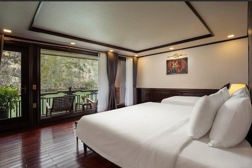 A hotel room with a large bed, a balcony with a view of greenery, and a painting on the wall. 2
