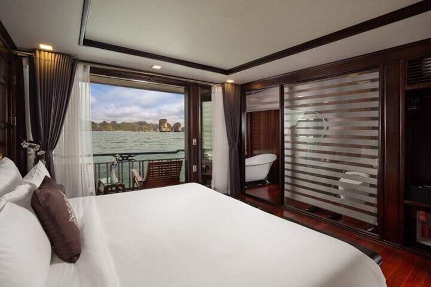 A large bed with white linens and a view of a body of water through a glass door. 3