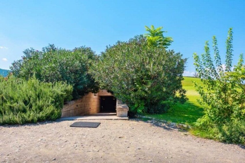 Ein schmaler Feldweg führt zu einem steinernen Torbogen, der von Grünpflanzen umgeben ist. 4