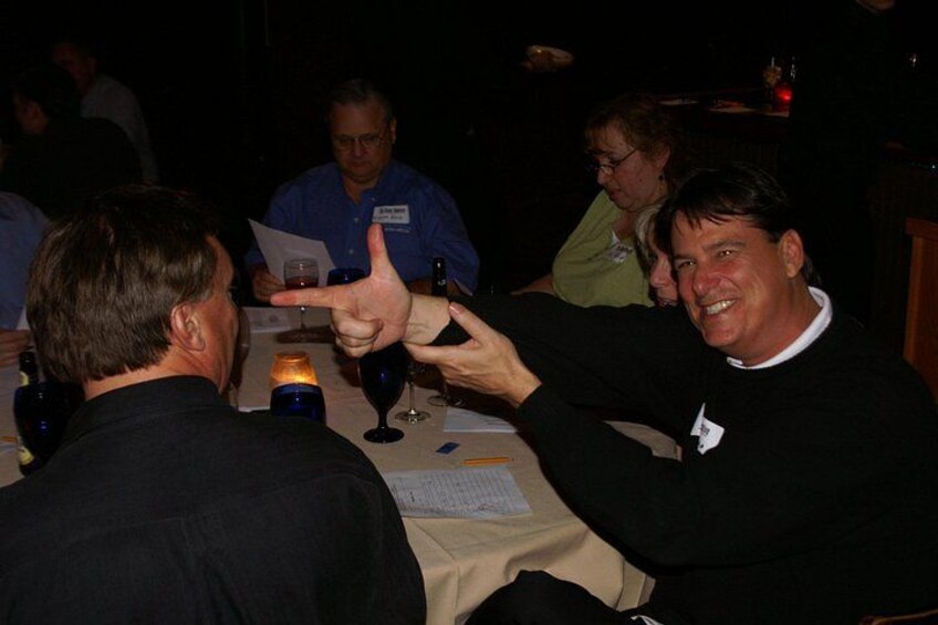 People sitting at a table with wine glasses and papers. 4